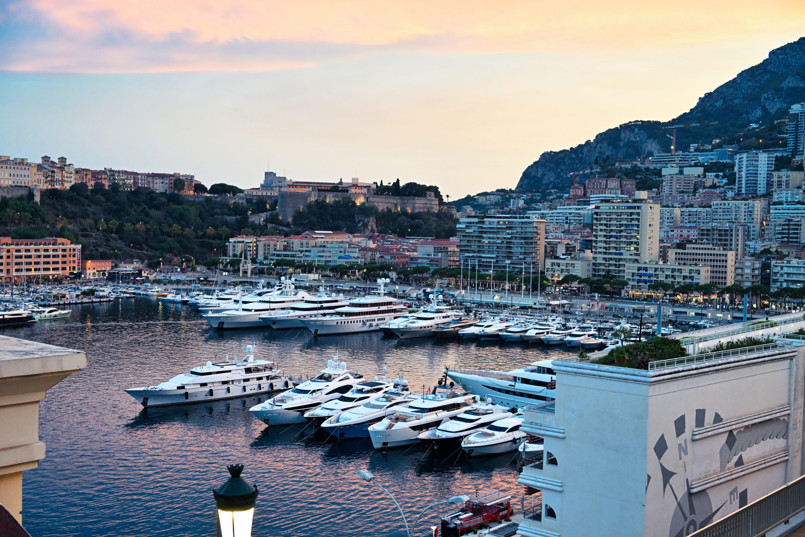 Cityscape of Monaco at sunset. Sea port with moored yachts, residential buildings and streets with illumination